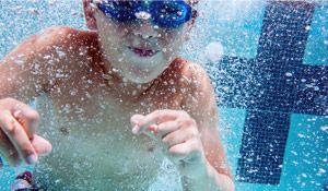 Boy underwater in a swimming pool at Outpost Summer Camp in San Diego